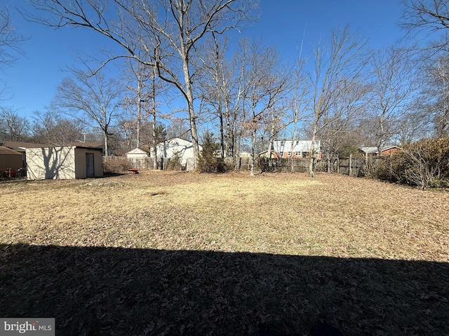 view of yard with a shed, an outdoor structure, and fence