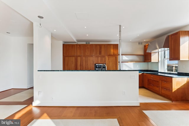 kitchen featuring hanging light fixtures, exhaust hood, and light hardwood / wood-style floors