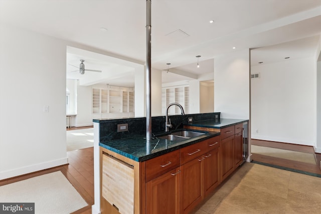 kitchen featuring sink, hanging light fixtures, ceiling fan, dark stone countertops, and beverage cooler