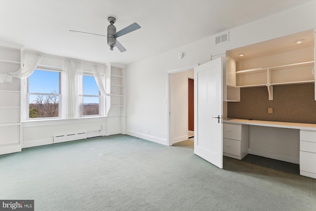 interior space with baseboard heating, ceiling fan, carpet flooring, and built in desk