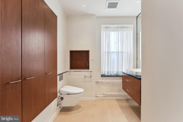 bathroom with vanity, toilet, and radiator