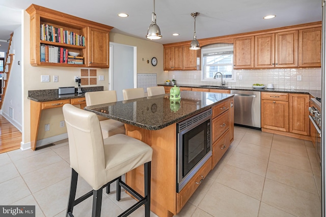 kitchen with a center island, pendant lighting, a breakfast bar, light tile patterned flooring, and appliances with stainless steel finishes