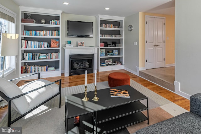 living room with built in shelves and light hardwood / wood-style flooring