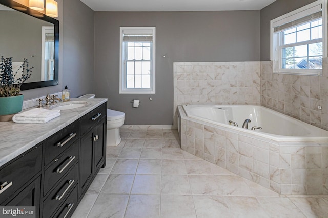 bathroom with tile patterned flooring, vanity, tiled bath, and toilet