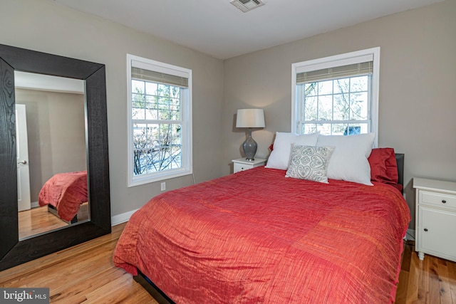 bedroom with hardwood / wood-style flooring and multiple windows