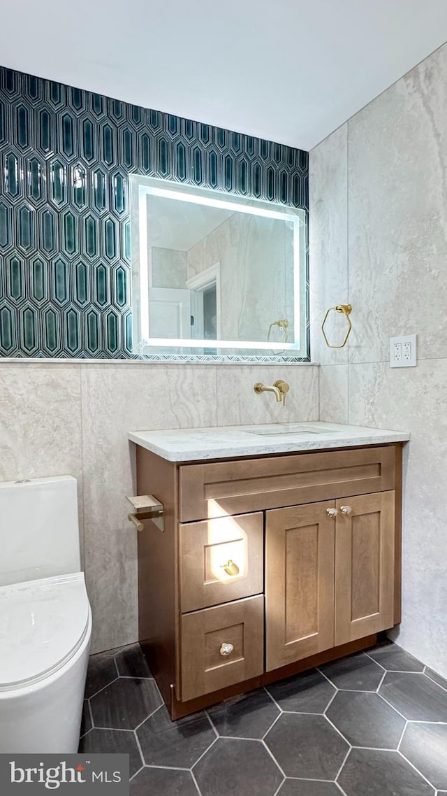 bathroom featuring tile patterned floors, toilet, tile walls, and vanity