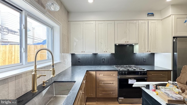 kitchen with a sink, white cabinets, tasteful backsplash, and stainless steel appliances