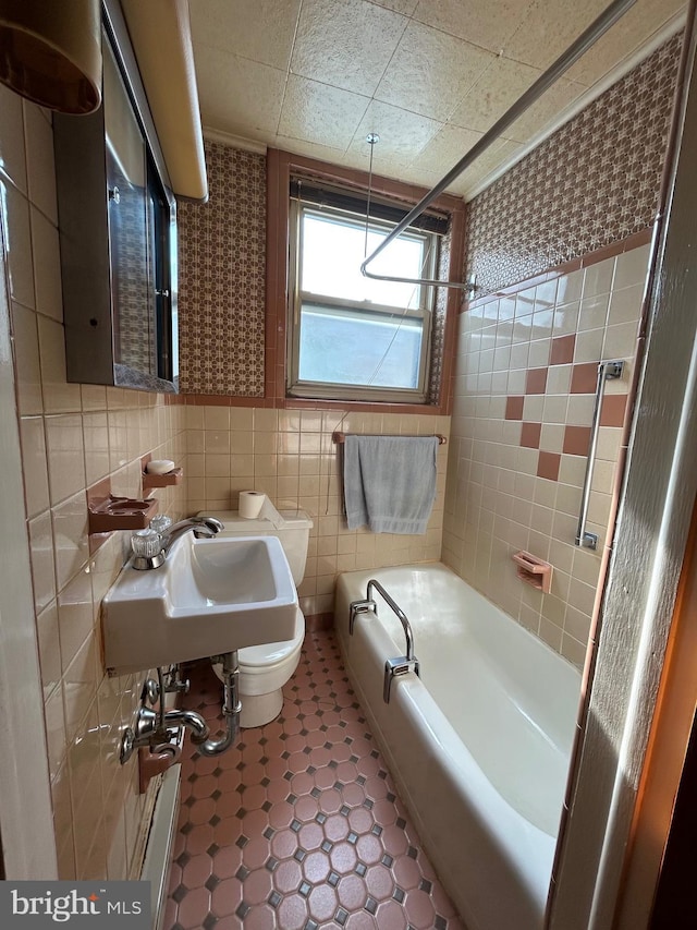 bathroom featuring sink, tile walls, and a tub to relax in