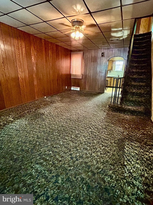 carpeted spare room with a baseboard radiator and wood walls