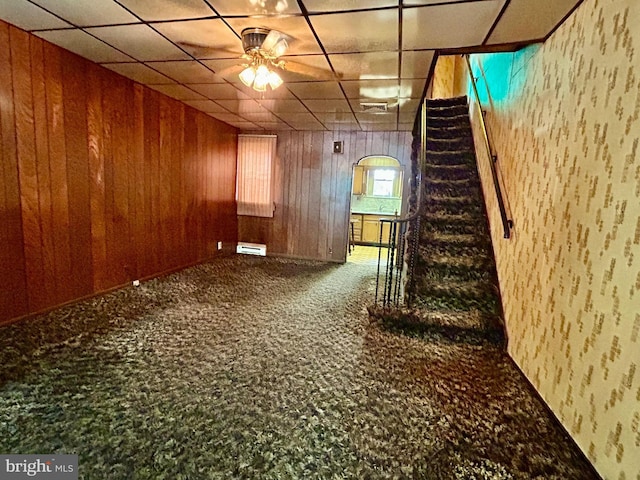 basement featuring wooden walls, a baseboard radiator, and carpet flooring