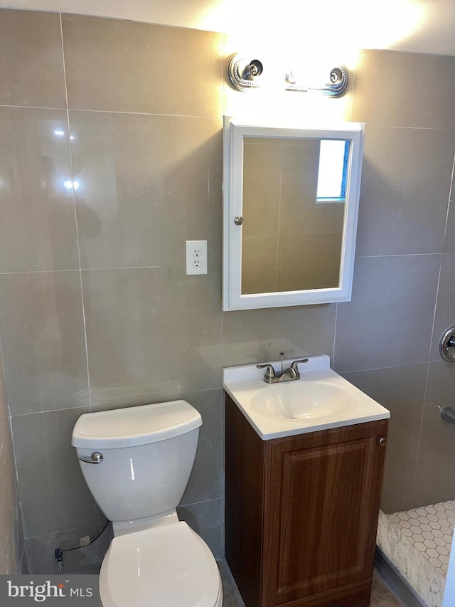 bathroom with vanity, toilet, and tile walls