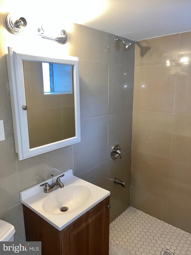 bathroom featuring vanity, toilet, and tile walls