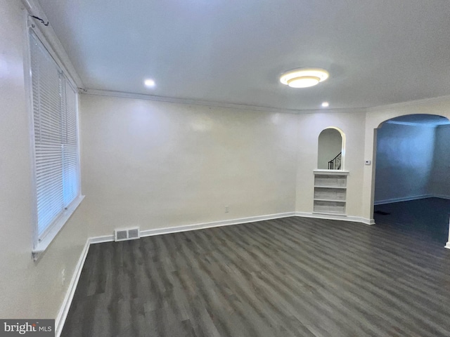 empty room with crown molding and dark wood-type flooring