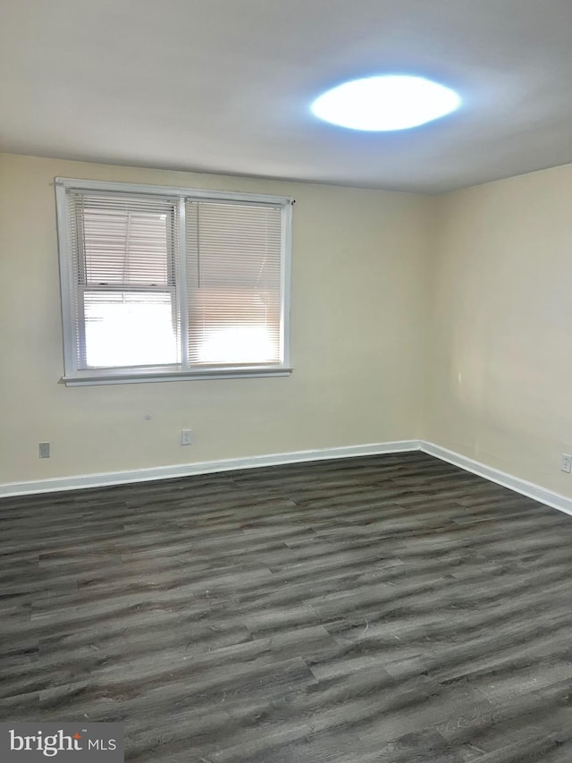 empty room with dark hardwood / wood-style flooring and a wealth of natural light