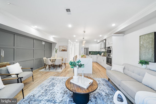 living room featuring light wood-type flooring and crown molding