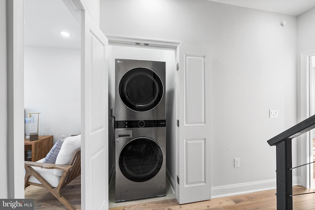 clothes washing area with stacked washer / dryer and light wood-type flooring