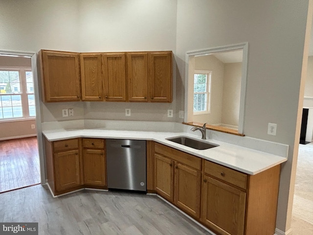 kitchen featuring a wealth of natural light, sink, stainless steel dishwasher, and light hardwood / wood-style flooring