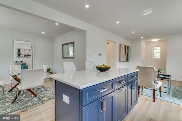 kitchen with blue cabinetry, light wood-type flooring, and a kitchen island