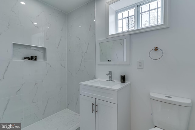 bathroom featuring tiled shower, vanity, and toilet