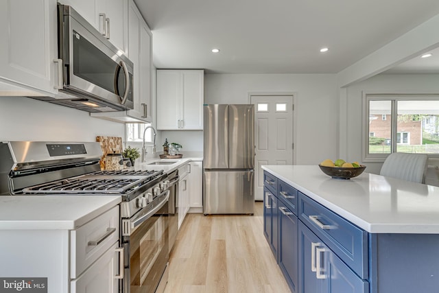 kitchen featuring white cabinetry, sink, stainless steel appliances, blue cabinets, and light hardwood / wood-style floors