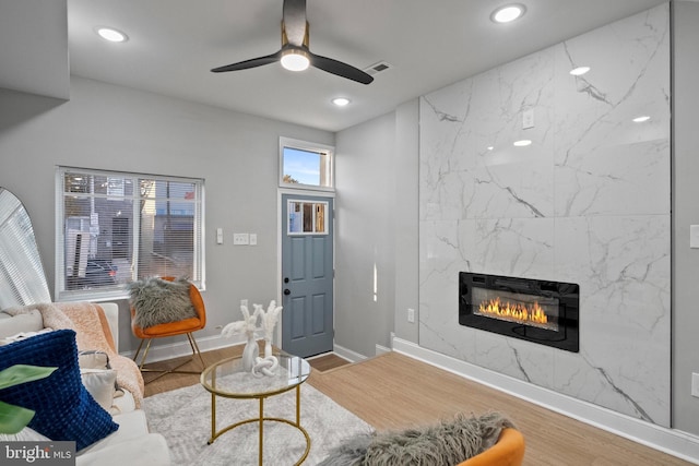 living room featuring hardwood / wood-style flooring, ceiling fan, and a premium fireplace