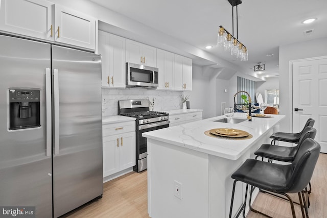 kitchen featuring stainless steel appliances, white cabinetry, a kitchen island with sink, and sink