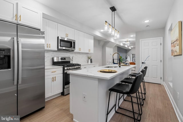 kitchen with a kitchen island with sink, sink, white cabinets, and stainless steel appliances