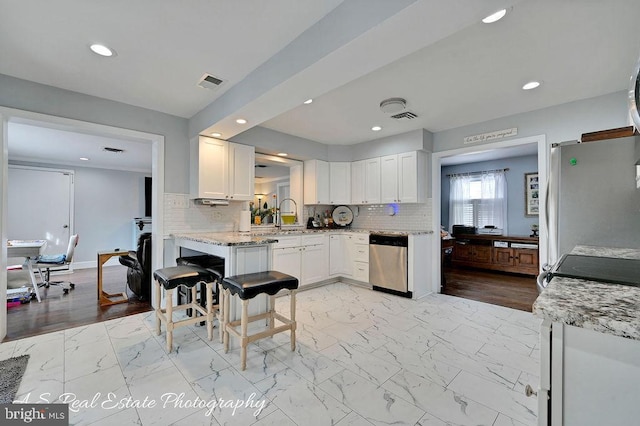 kitchen with light stone countertops, white cabinetry, appliances with stainless steel finishes, and tasteful backsplash