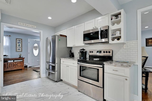 kitchen with light stone countertops, appliances with stainless steel finishes, tasteful backsplash, and white cabinetry