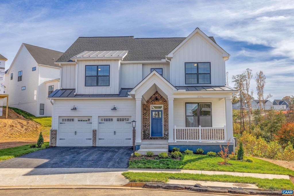 modern farmhouse featuring a porch, a garage, and a front yard