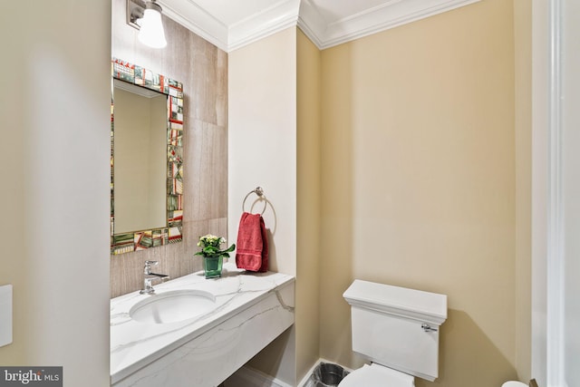 half bathroom featuring ornamental molding, vanity, and toilet