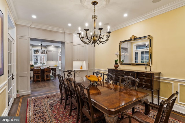 dining area with a wainscoted wall, dark wood finished floors, a notable chandelier, a decorative wall, and ornamental molding