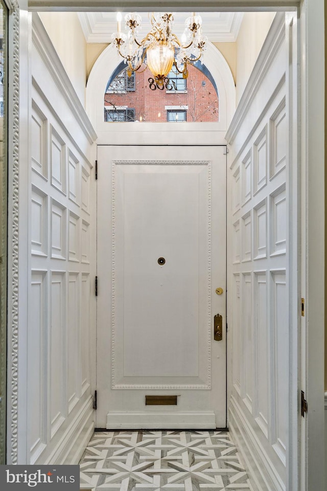 doorway featuring an inviting chandelier and crown molding