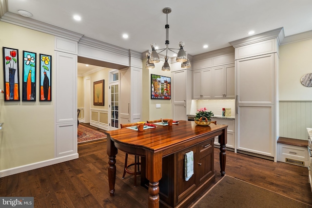 interior space featuring dark wood-style floors, decorative light fixtures, crown molding, recessed lighting, and wainscoting