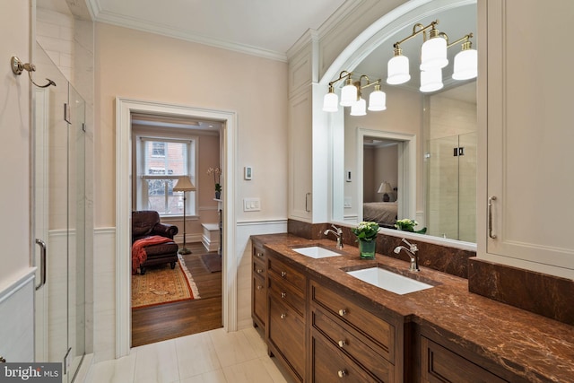 bathroom with ensuite bathroom, ornamental molding, a stall shower, and a sink