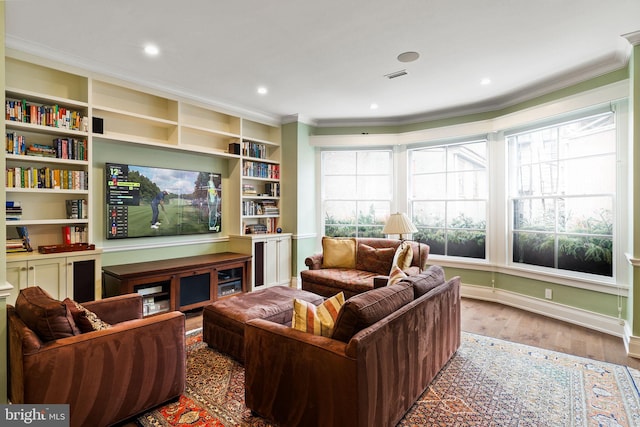 living area with ornamental molding, wood finished floors, visible vents, and baseboards