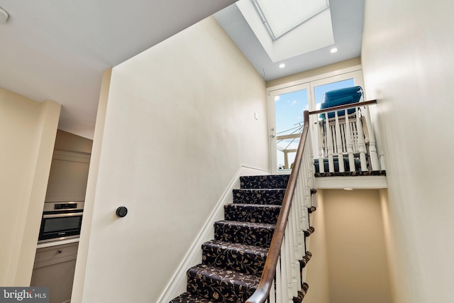 stairway featuring recessed lighting, a skylight, and baseboards