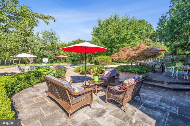 view of patio featuring a deck, outdoor dining space, fence, a fenced in pool, and an outdoor hangout area