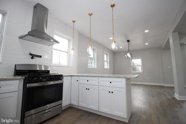 kitchen with dark wood-type flooring, white cabinets, wall chimney range hood, stainless steel gas stove, and decorative light fixtures