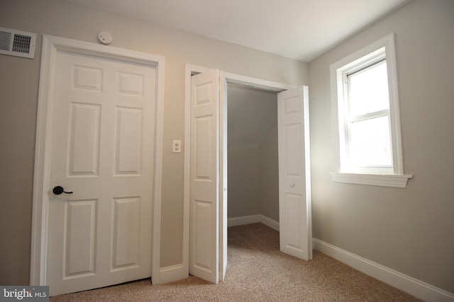 unfurnished bedroom with light colored carpet and a closet