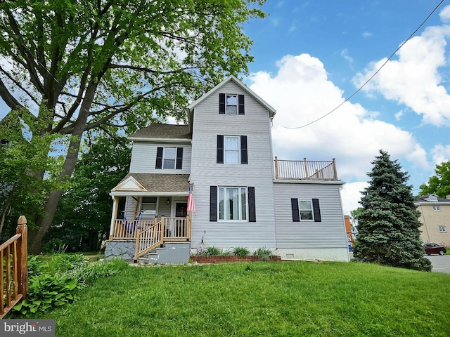 view of front of house featuring a front yard, a balcony, and covered porch