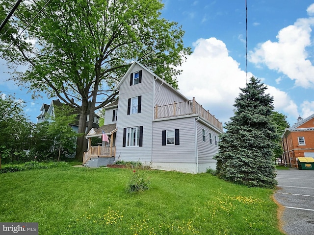 view of side of property with a balcony and a yard