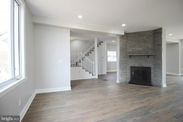 unfurnished living room featuring hardwood / wood-style floors and a stone fireplace