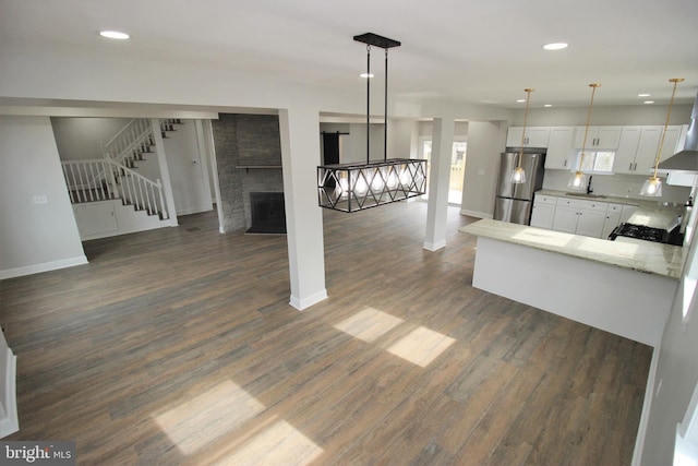 kitchen featuring stainless steel refrigerator, white cabinetry, dark wood-type flooring, tasteful backsplash, and a fireplace