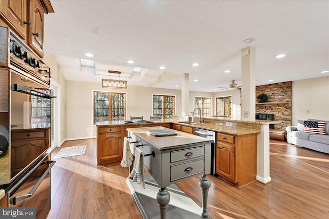 kitchen featuring kitchen peninsula, light hardwood / wood-style flooring, stainless steel dishwasher, and sink