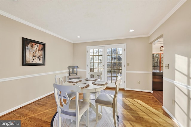 dining room with wood-type flooring, french doors, and ornamental molding