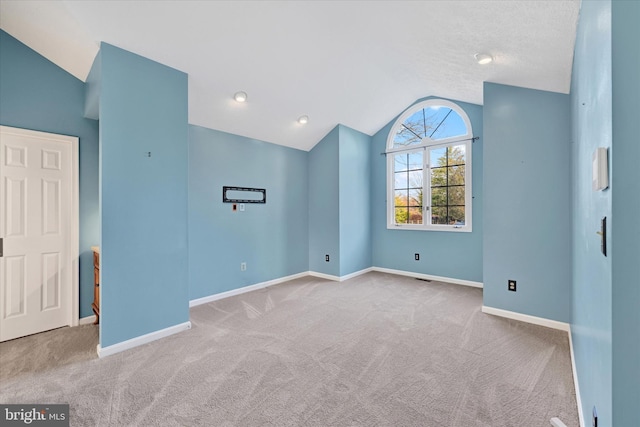 spare room with light colored carpet and vaulted ceiling