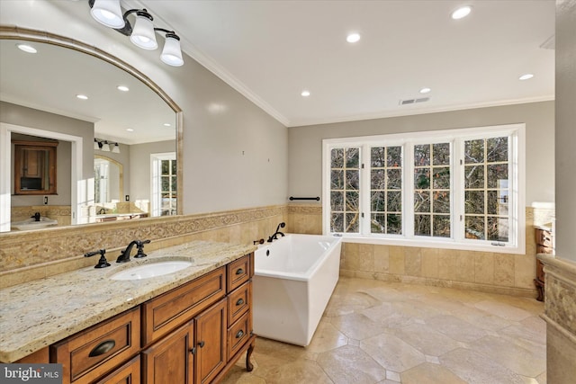 bathroom with vanity, ornamental molding, and a tub to relax in