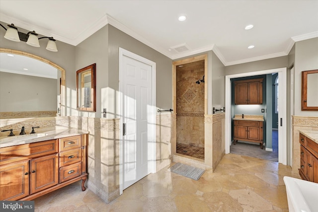 bathroom featuring vanity, a tile shower, and ornamental molding