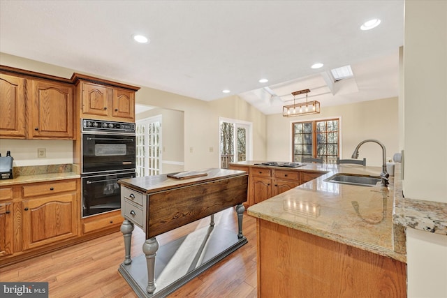 kitchen featuring gas cooktop, black double oven, sink, pendant lighting, and light hardwood / wood-style flooring